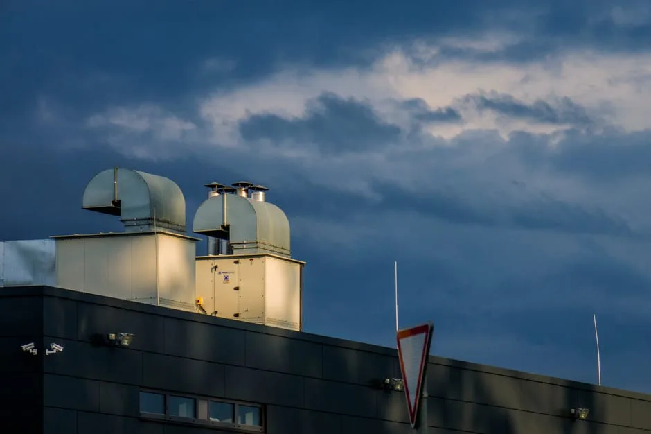 Low-angle view of industrial ventilation pipes and exhaust fans on a commercial rooftop