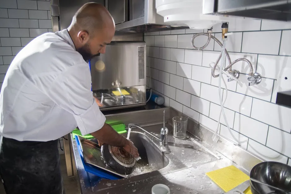 Commercial kitchen worker maintaining hood filter equipment